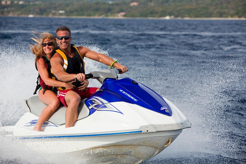 couple racing around on a jet ski in Roatan Honduras