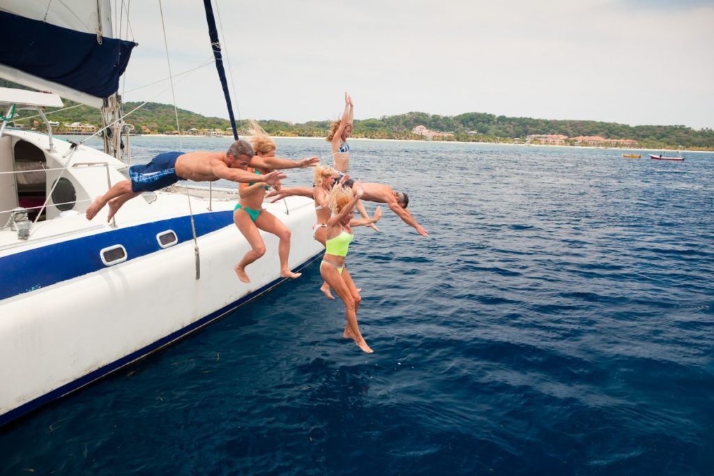 friends jumping off a catamaran - fun things to do in Roatan