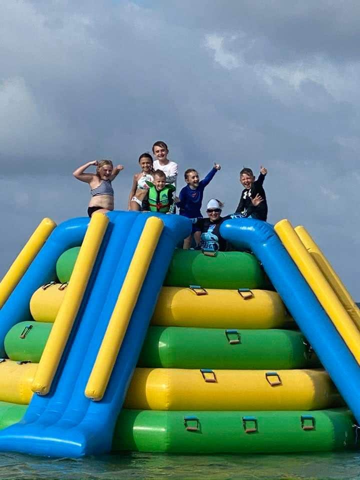 smiling kids on top of an inflatable in the sea